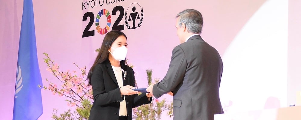 A girl handing documents to a man on the stage at the UN Kyoto Congress