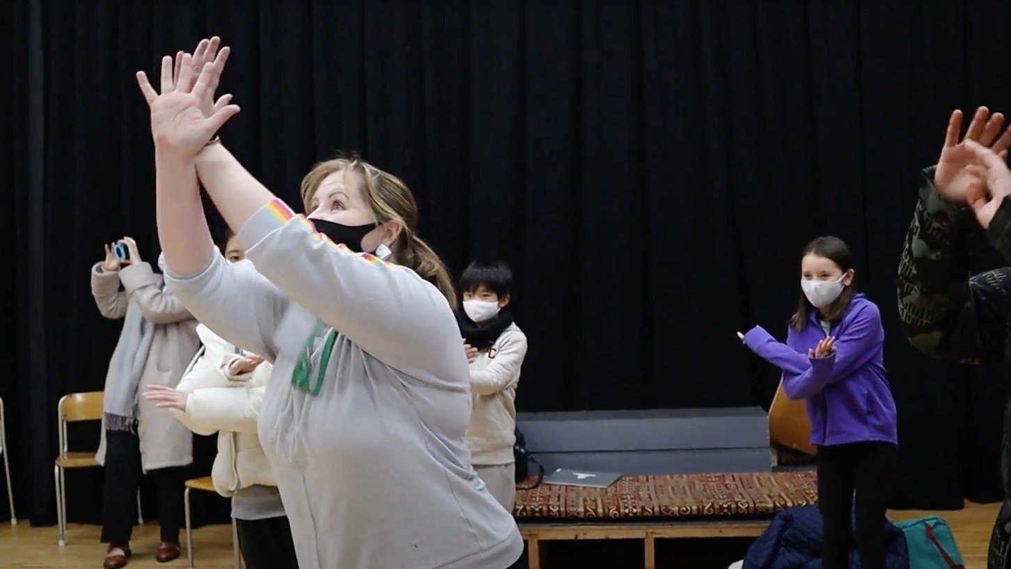 Drama teacher demonstrating a dramatic pose in front of her students.