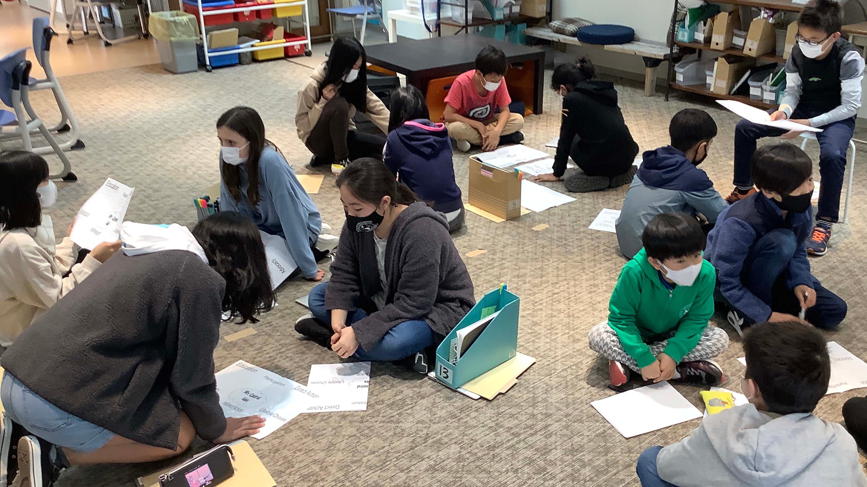 Students gathered on the floor working together on a lesson.