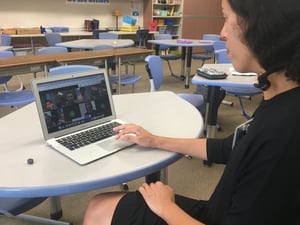 teacher sitting in front of a computer meeting with her class online