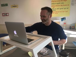 A teacher talking with a student and his parents during an online meeting