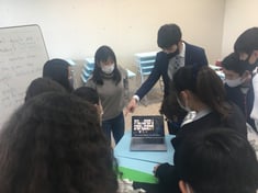 A boy is showing a computer screen to a group of students