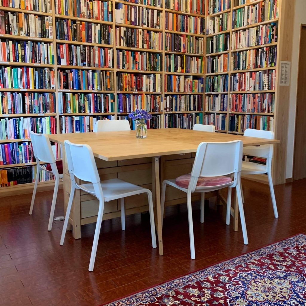 A table and chairs are surrounded by bookshelves full of books.