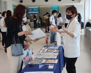 A student and her mother talk with a representative of a university at a college fair.