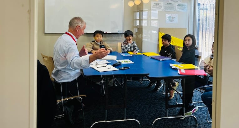 A CIS evaluator speaks with children around a table in the conference room.