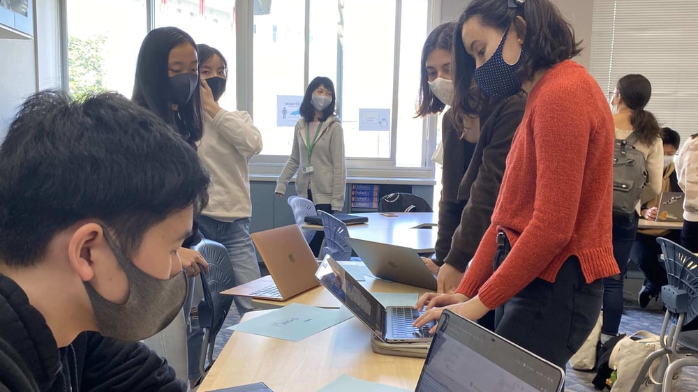 Students gather in a classroom around their computers as they prepare for the Model United Nations